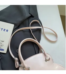 Detail of light pink shell bag showing smooth leather texture and adjustable strap