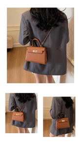 Close-up of brown leather Kelly handbag with gold lock and metal chain strap details