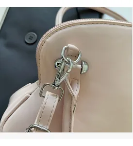 Macro shot of silver spring hook and stitching on pink shell bag shoulder strap