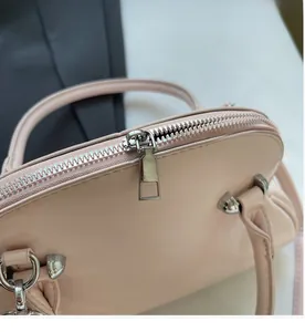 Detail shot of smooth silver zipper and soft pink faux leather on shell bag
