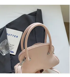 Detail of light pink shell handbag featuring smooth dual handles and silver hardware