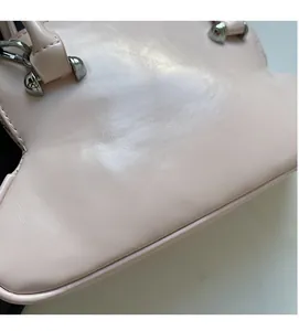 Detail shot of the soft pink leather texture and silver metal buckles on the handbag