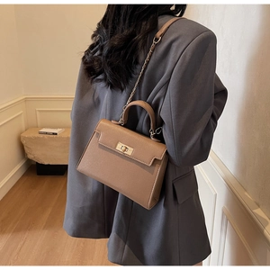 Khaki pebbled leather bag with gold twist lock shown on model with chain strap