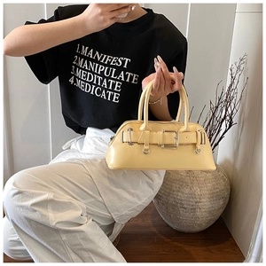 Détail d'un sac à main en cuir jaune avec boucle métallique et poignées rondes