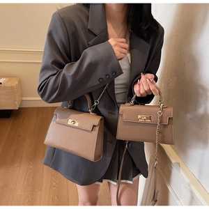 Detail view of large and small tan crossbody bags with gold hardware and chain straps