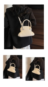 Rear view of a white shell-shaped glossy handbag styled with a black blazer and white skirt