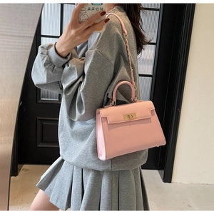 Detailed close-up of pink pebbled leather Kelly bag with golden twist lock and chain strap
