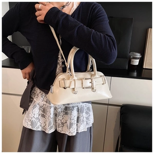 Sac à main blanc crème en similicuir avec boucle en métal, porté dans un décor de café