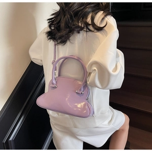 Purple patent leather shell bag with wave base shown worn crossbody by a model