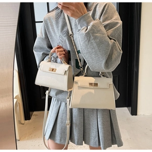 Detail shot of two cream lychee grain leather handbags with golden twist locks and straps