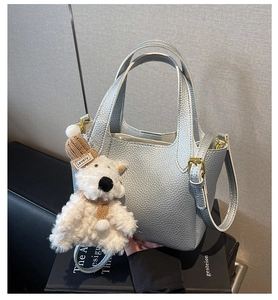 Close-up of silver lychee texture leather bucket bag with a cute plush puppy charm