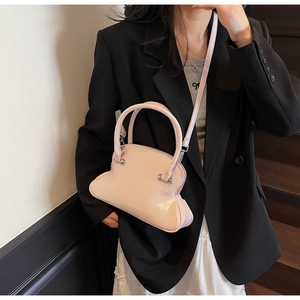 Pink shell shaped crossbody bag with glossy finish and silver hardware on female model