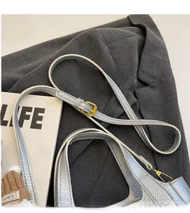 Detail of silver lychee pattern leather handbag with adjustable golden buckle strap