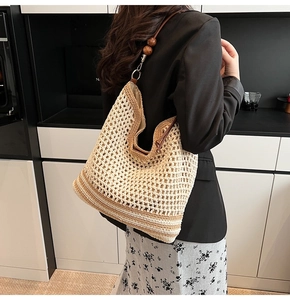 Close-up of hollow straw tote bag featuring leather strap and decorative wood beads