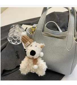 Close-up of silver-gray lychee pattern leather bucket bag with plush bear charm accessory