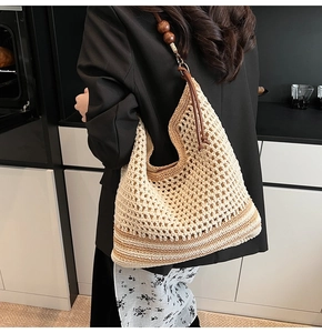 Close-up of hollow woven tote bag with wooden bead strap detail on a female model