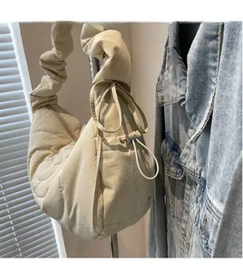 Detail shot of the pleated wide shoulder strap and drawstring toggle on the beige nylon bag