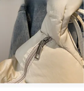 Macro detail of high-quality smooth silver metal zipper on cream quilted dumpling bag