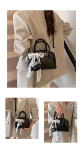 Détail du mini sac oreiller noir avec nœud en dentelle et pendentif cœur sur le mannequin