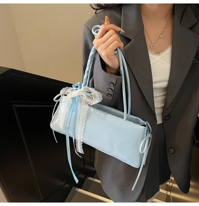 Detail of light blue patent leather underarm bag with white lace bow decoration