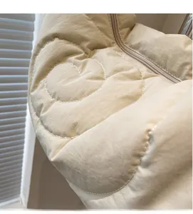 Detail of beige nylon bag showing heart-shaped quilting and smooth zipper texture