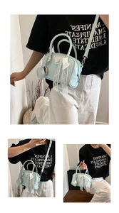 Détail du sac polochon bleu clair avec nœud en dentelle blanche et breloque en forme de cœur