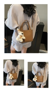 Close-up of brown litchi pattern leather bucket bag with a cute plush bear charm accessory