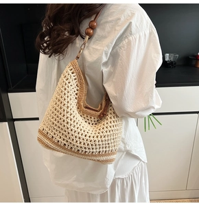 Detail of hand-woven straw tote bag featuring dark wooden beads and gold metal buckle