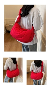 Detail view of red quilted crescent shoulder bag with plush nylon texture and wide strap