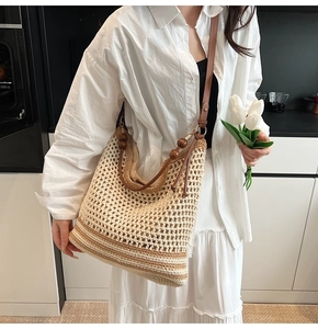 Detail of hollow straw tote bag with brown leather straps and decorative wooden beads