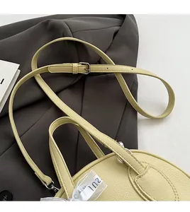 Close-up of pale yellow lychee grain leather handbag with decorative printed ribbon