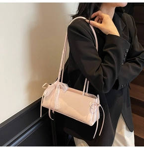 Detail of pink patent leather baguette bag with lace bow and drawstring side