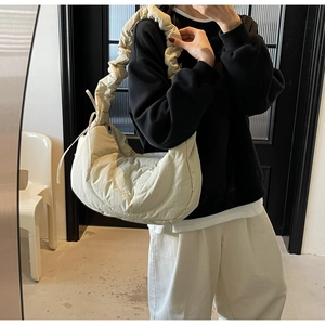 Close-up of pleated shoulder strap and creamy crescent cloud bag on model side view