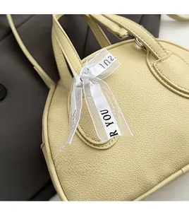 Close-up of lychee grain leather texture and decorative ribbon on yellow handbag