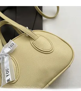 Detail of lychee pattern leather handbag featuring smooth manual stitching and silk ribbon