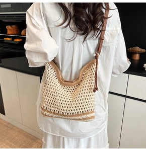 Detailed side view of a beige crochet tote bag with brown leather straps and woven mesh