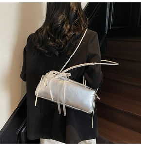 Detail view of silver metallic shoulder bag with white lace bow and silk ribbons