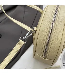 Detail of detachable strap hook and silver zipper on beige faux leather bag