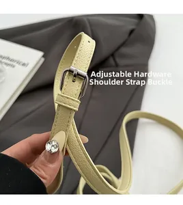 Detail of adjustable litchi texture leather strap with silver metal buckle on handbag