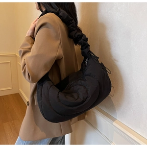 Detail of ruffled shoulder strap and quilted nylon texture on a black crescent bag