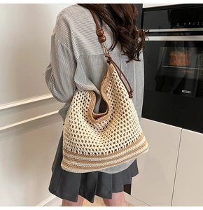 Detail of hollow woven shoulder bag with wooden bead accents and striped contrast base
