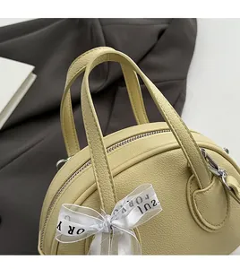 Close-up of cream lychee texture leather bowling bag with stylish bow ribbon detail