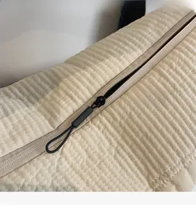 Detail of smooth black zipper closure on beige quilted fabric of large tote bag