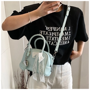 Détail du sac bandoulière vert menthe avec nœud en dentelle blanche et pendentif coeur