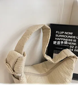 Detail of beige quilted shoulder bag featuring unique thick rope knotted handle design