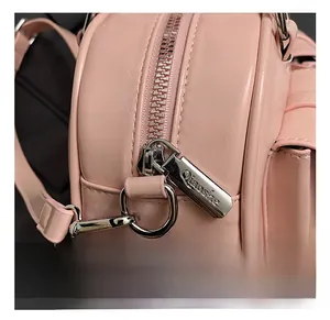 Close-up of pink leather handbag showing silver zipper hardware with engraved logo