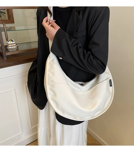 Close-up of white crescent crossbody bag featuring YIYUAN label and minimalist zipper design