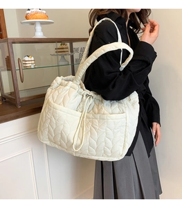 Detail of off-white quilted puffer tote bag with side pocket and drawstring closure