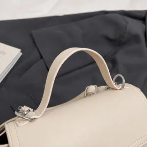 Détail de la poignée du sac en cuir beige avec anneaux en D argentés et finitions soignées