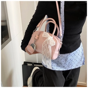 Sac bowling rose avec nœud en dentelle blanche et breloque cœur porté en bandoulière
